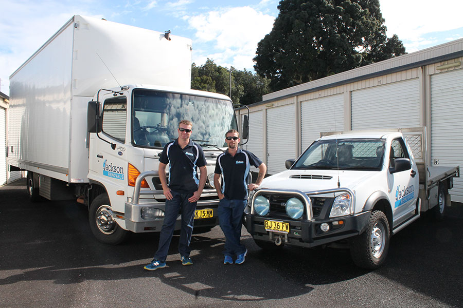 Two removalists in front of removalist truck and ute